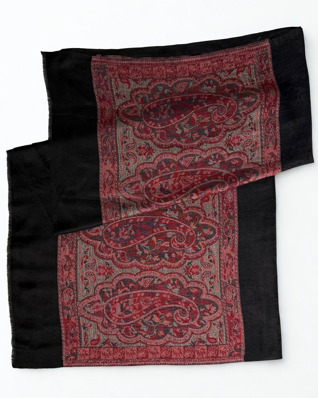 Black pashmina ring shawl draped over a wooden hanger, self-woven paisley ground falling into a deep crimson end panel