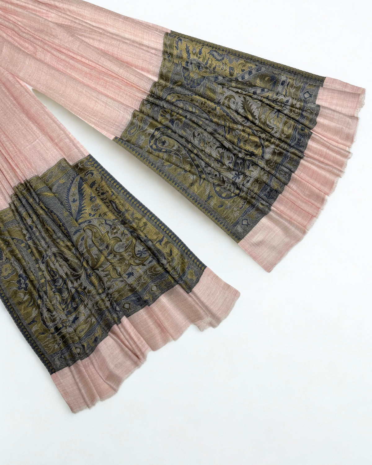 Close view of both ends of the blush pink Palladar ring shawl, showing the woven paisley pallas in olive, moss and indigo with pink borders and fringe