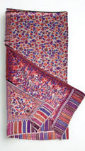 Blush Kani pashmina shawl laid flat, handwoven purple, coral and red floral field with a striped arched end border