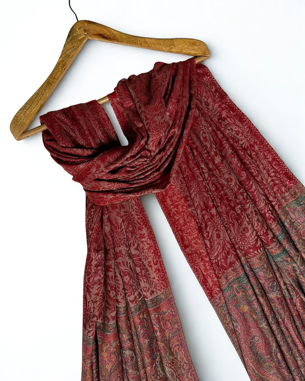 Red Palladar shawl on a wooden hanger showing its full drape and both end borders