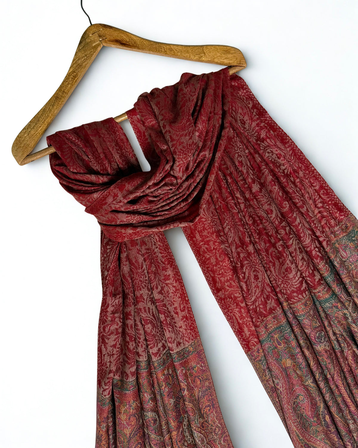 Red Palladar shawl on a wooden hanger showing its full drape and both end borders