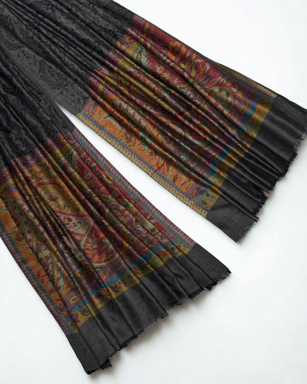 Close-up of both ends of a dark charcoal pashmina ring shawl, showing the saffron, crimson, lilac and teal woven paisley pallas