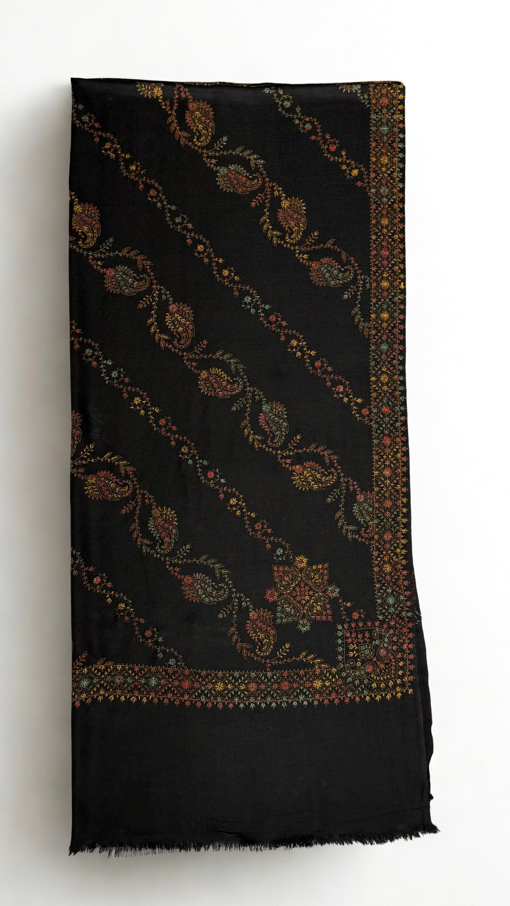 Black Swati Shahtoosh shawl folded, showing diagonal rows of hand-embroidered paisley and vine, corner medallion, embroidered border and plain fringed end