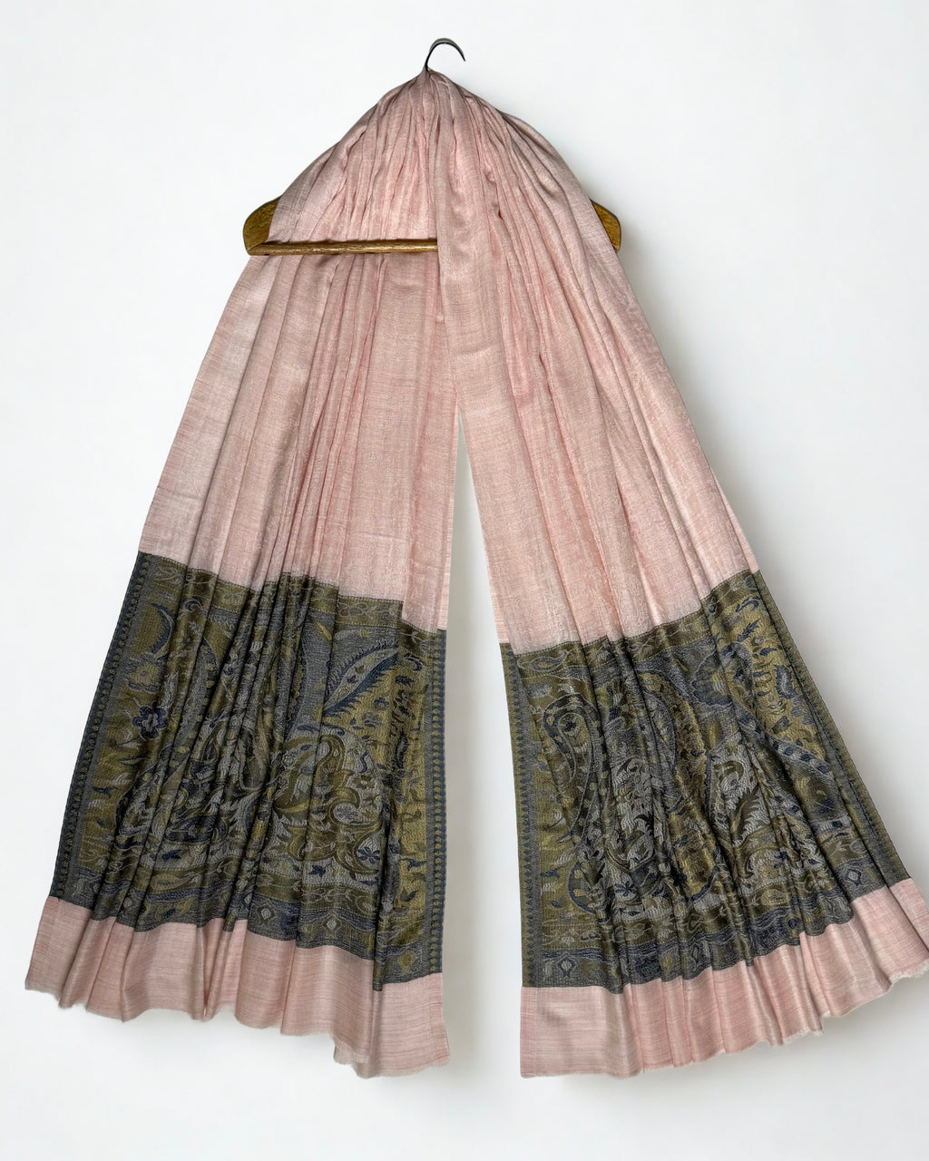 Blush pink Palladar ring shawl hanging from a wooden hanger, both woven paisley pallas visible at the ends