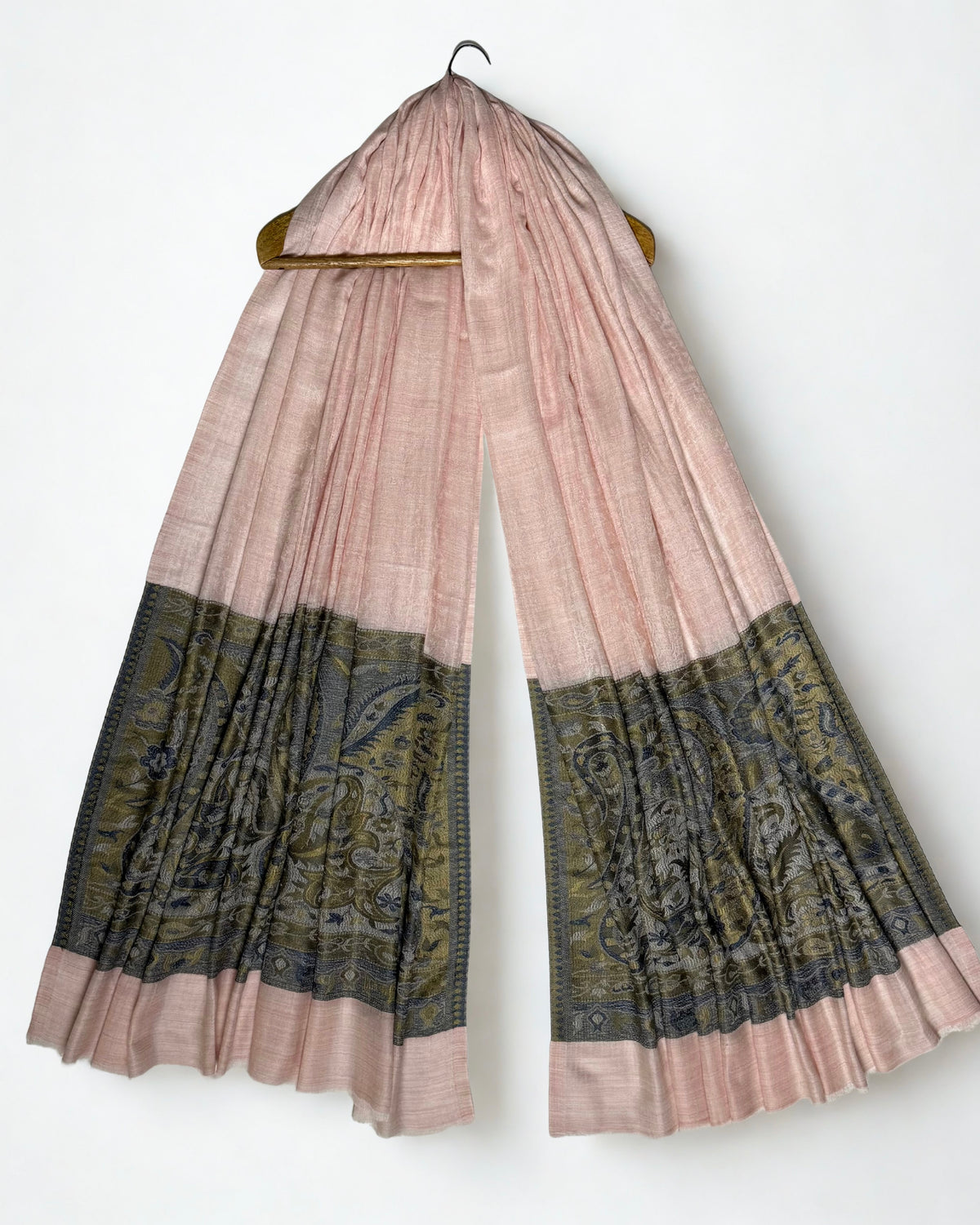 Blush pink Palladar ring shawl hanging from a wooden hanger, both woven paisley pallas visible at the ends