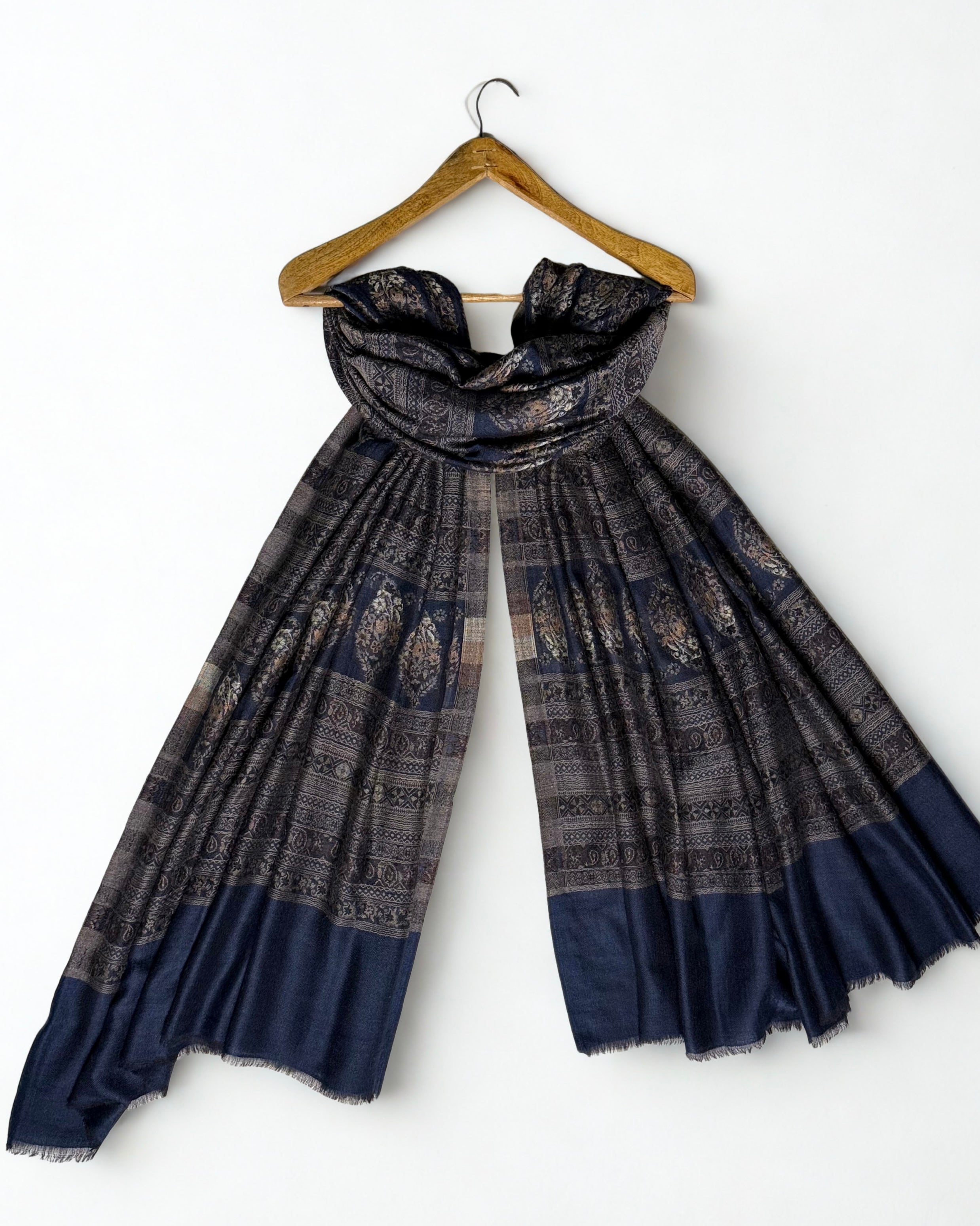 Indigo and bronze Indian pashmina shawl laid flat, banded rows of large floral buta on indigo with fine geometric stripes and a plain indigo end panel