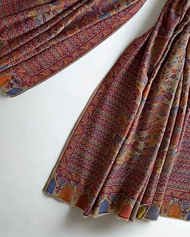 Detail of the small scattered flowers and large blown roses woven in rose, cornflower and gold on a stone pashmina ground