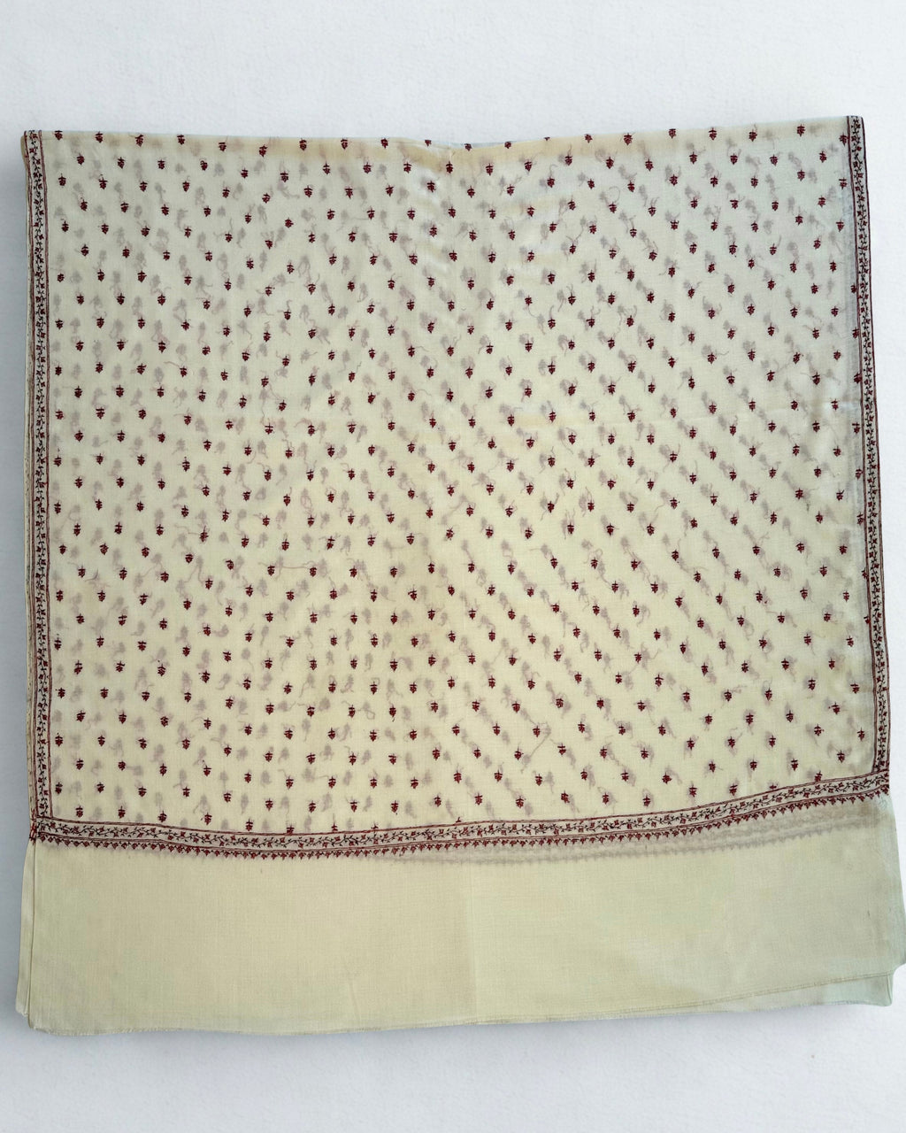 Ivory pashmina shawl draped in soft folds, showing the crimson border and scattered buti