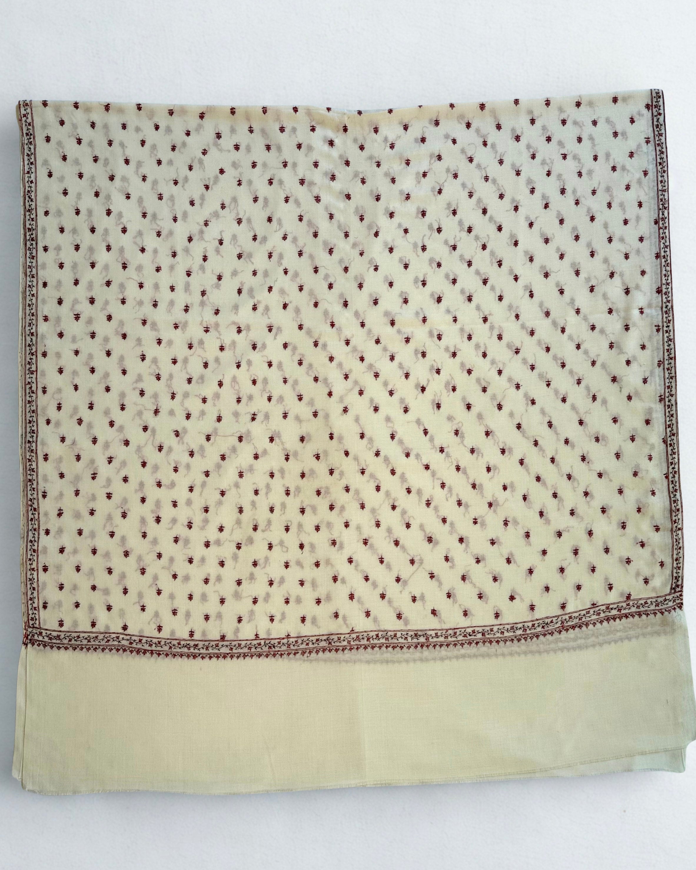 Ivory pashmina shawl draped in soft folds, showing the crimson border and scattered buti