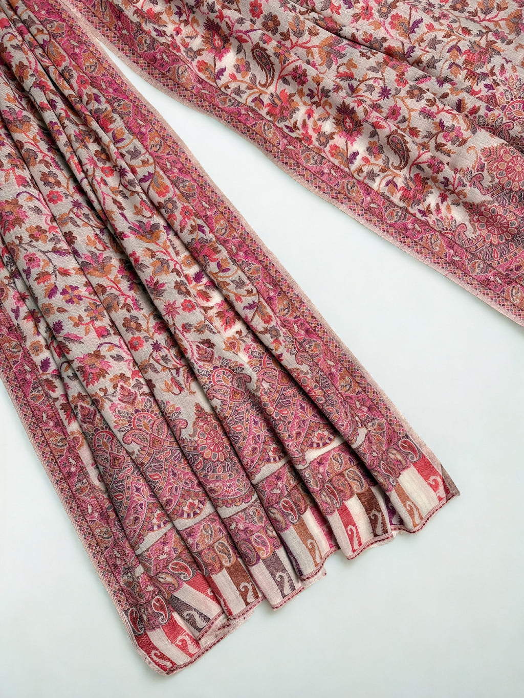 Detail of the scalloped medallion border and striped paisley end panel on an oyster Kani pashmina shawl