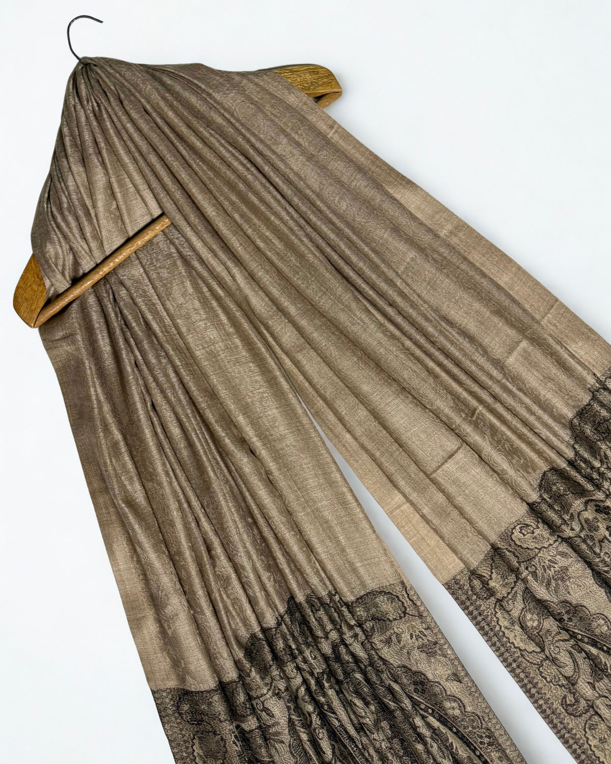 Fawn fine pashmina ring shawl on a wooden hanger at an angle, showing its soft sheen and dark paisley pallas