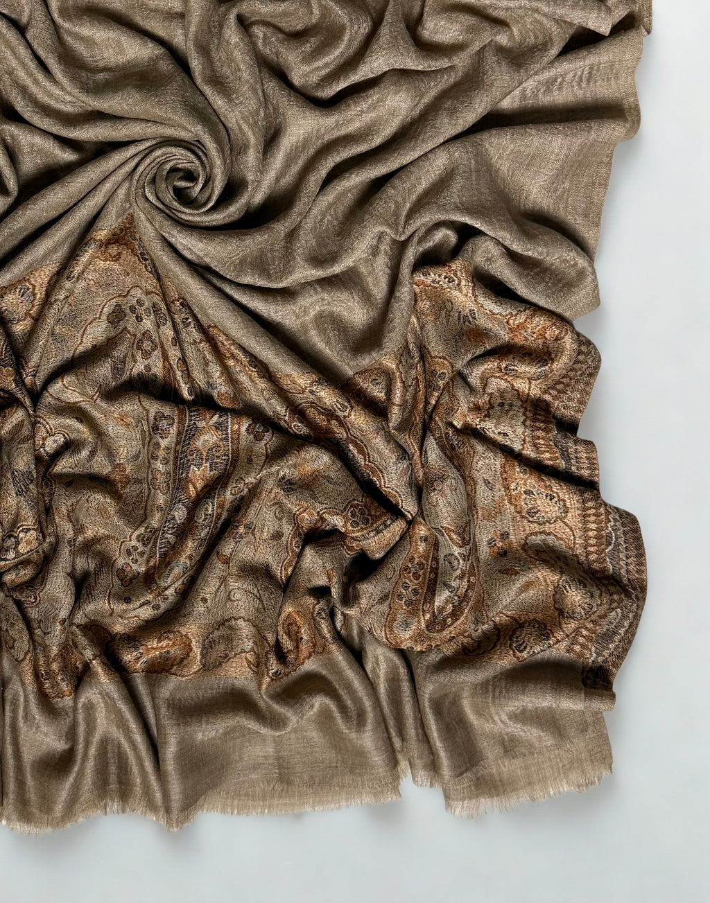 Close-up of a warm khaki Palladar shawl swirled to show the woven paisley palla and plain fringed end