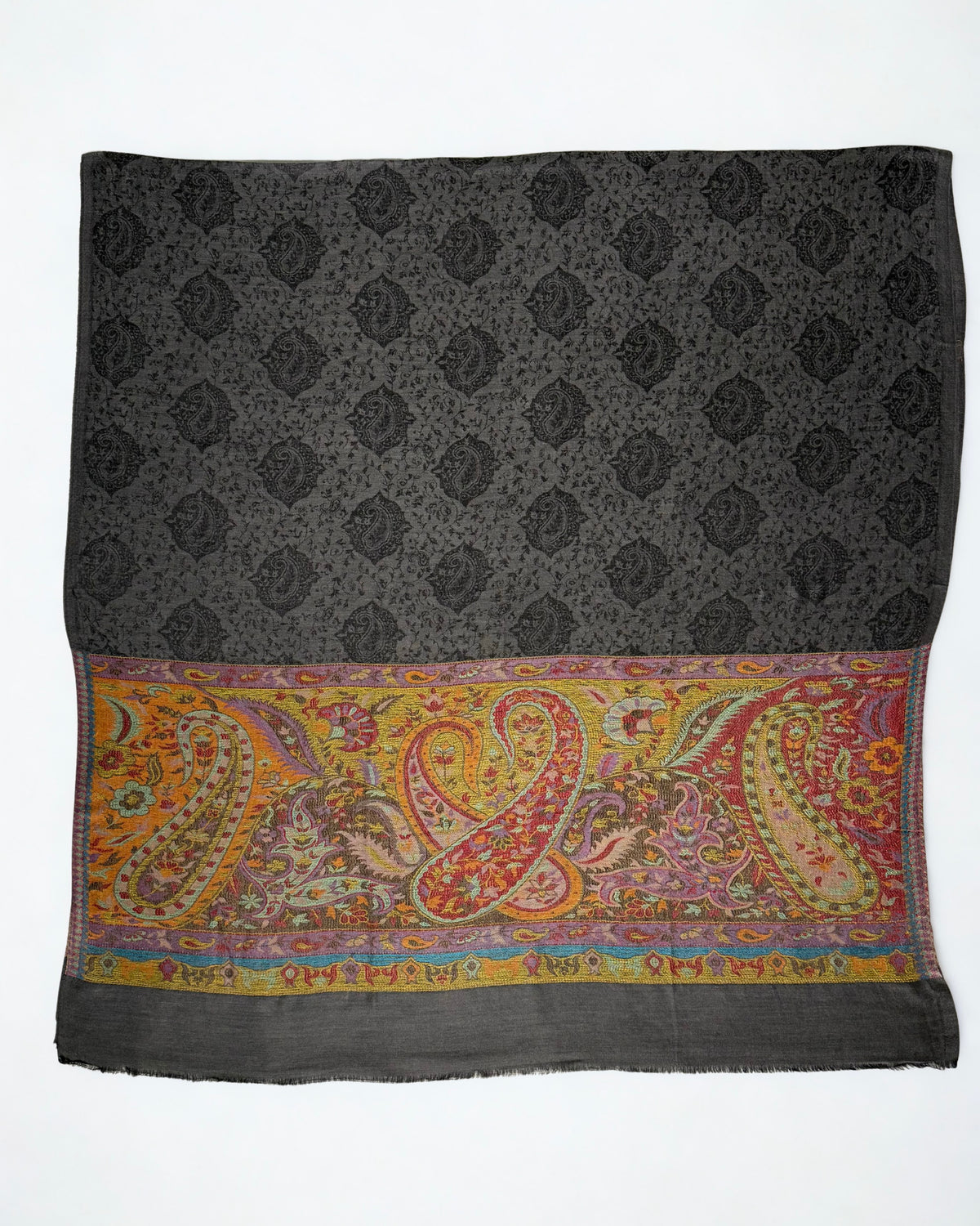 Dark charcoal pashmina ring shawl laid flat, showing the woven black paisley field and large interlocking paisleys across the saffron palla