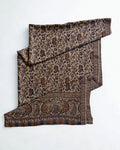 Sand-coloured Kani pashmina shawl laid flat, handwoven indigo and chestnut paisley field with a wide ornamented end border