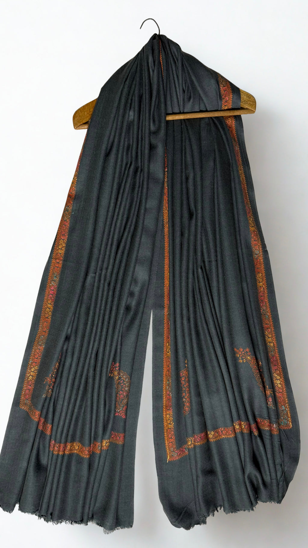 Charcoal Swati Shahtoosh shawl on a hanger, rust embroidered border running down both ends