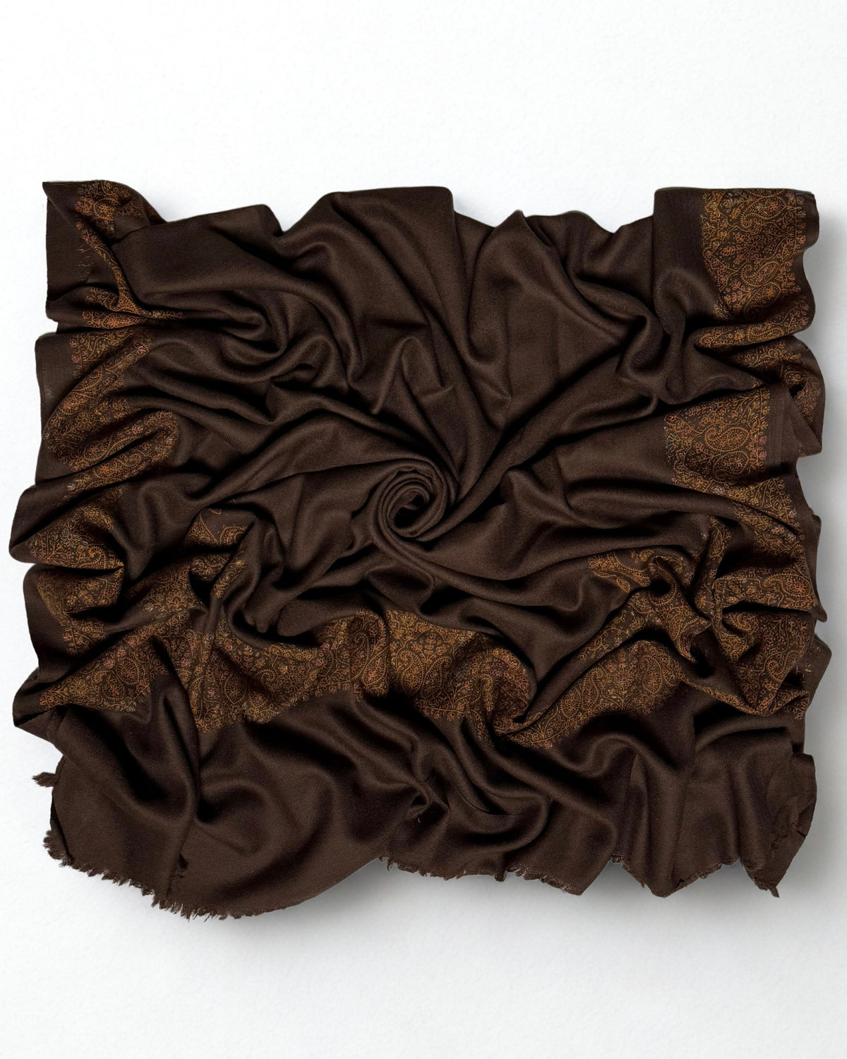 Espresso brown Swati Shahtoosh shawl gathered in folds, the gold and copper paisley border catching the light against the dark ground
