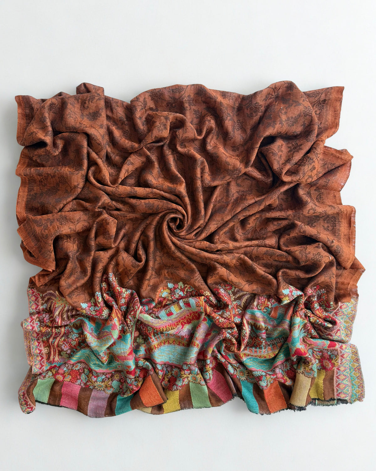 Shawl folded back to show where the rust field meets the woven scene