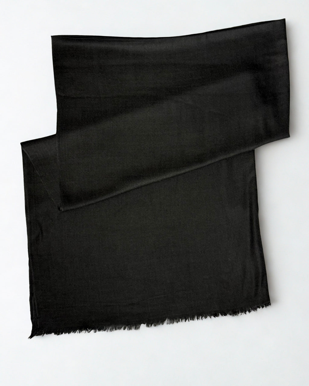 Charcoal black Swati Shahtoosh shawl folded diagonally on a white background, plain with a natural fringed edge