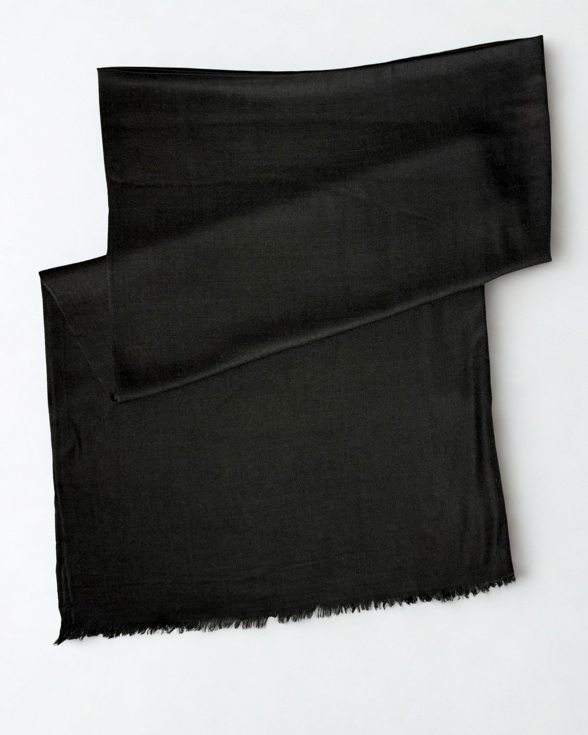 Charcoal black Swati Shahtoosh shawl folded diagonally on a white background, plain with a natural fringed edge