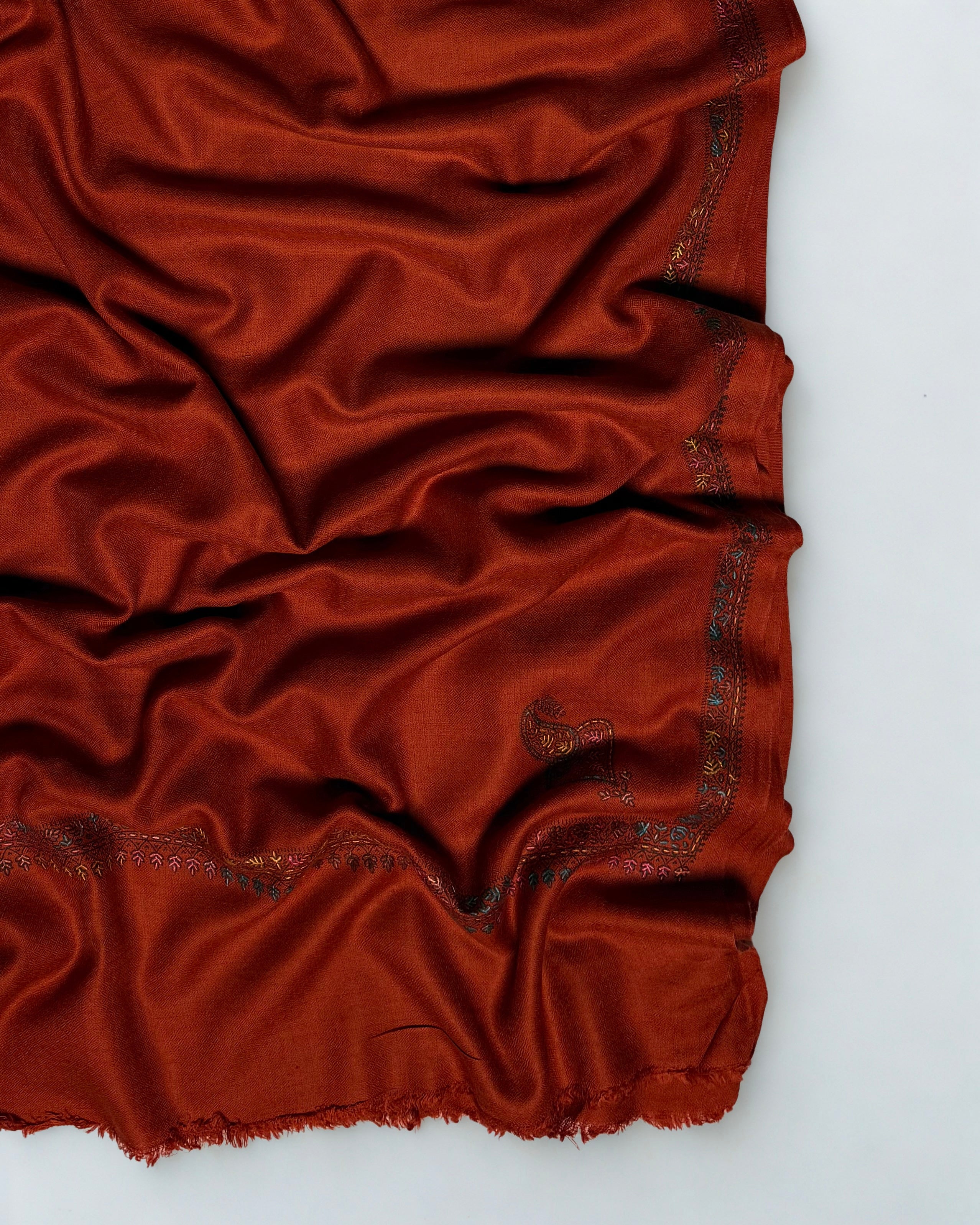 Rust Swati Shahtoosh shawl folded back to show both corner buta and the embroidered border meeting at the corner