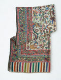 Ivory Kani shikargah pashmina shawl laid flat, birds, deer and leopards woven among flowering trees within four borders and a striped end panel