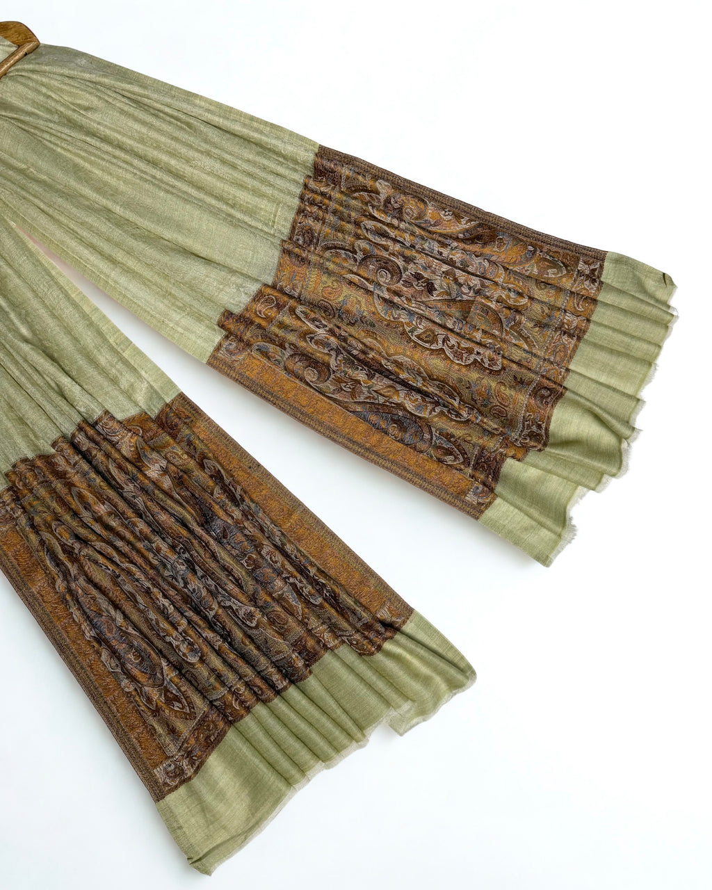 Close-up of both ends of a pistachio Palladar shawl, showing the woven bronze, ochre and brown paisley pallas