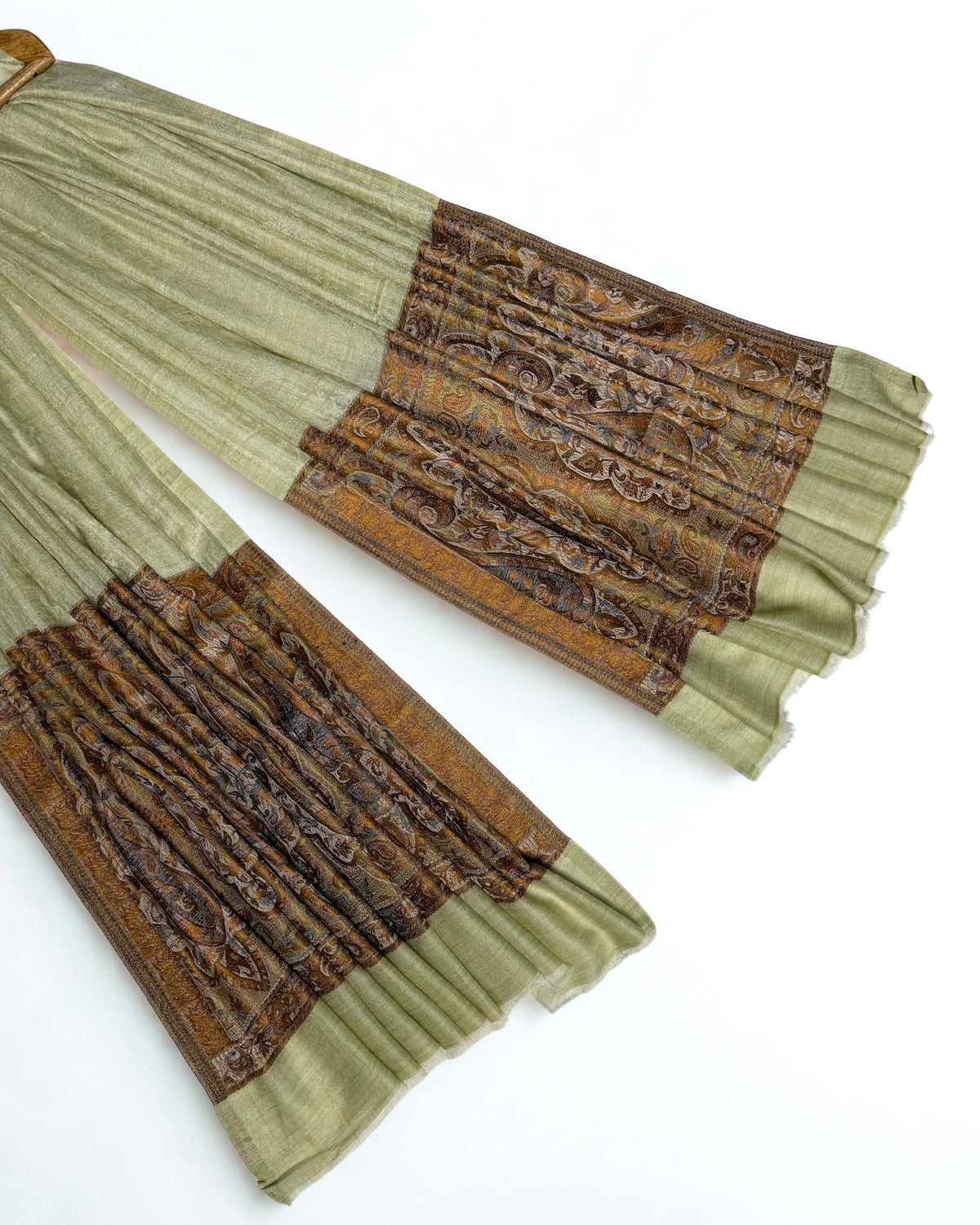 Close-up of both ends of a pistachio Palladar shawl, showing the woven bronze, ochre and brown paisley pallas