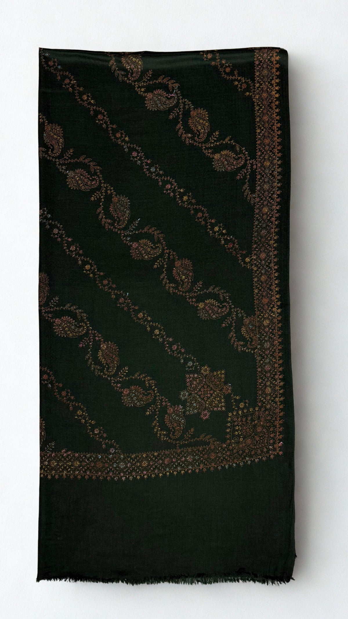 Forest green Swati Shahtoosh shawl folded, showing diagonal rows of hand-embroidered paisley and vine, corner medallion, embroidered border and plain fringed end