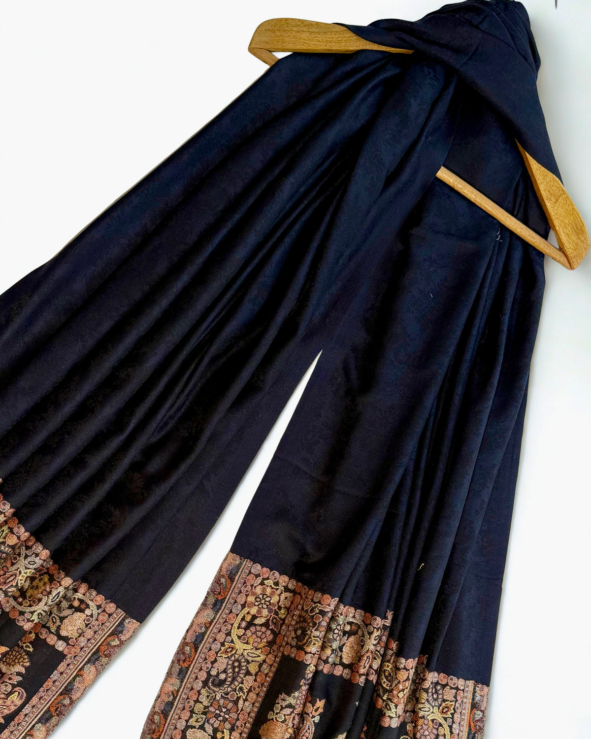 Navy pashmina shawl swirled to show its drape against the antique paisley border