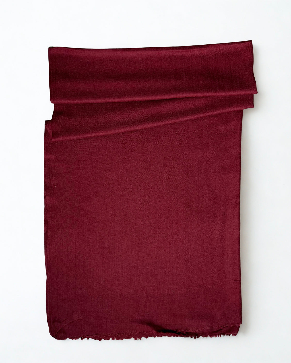 Maroon Swati Shahtoosh shawl folded on a white background, plain with a natural fringed edge