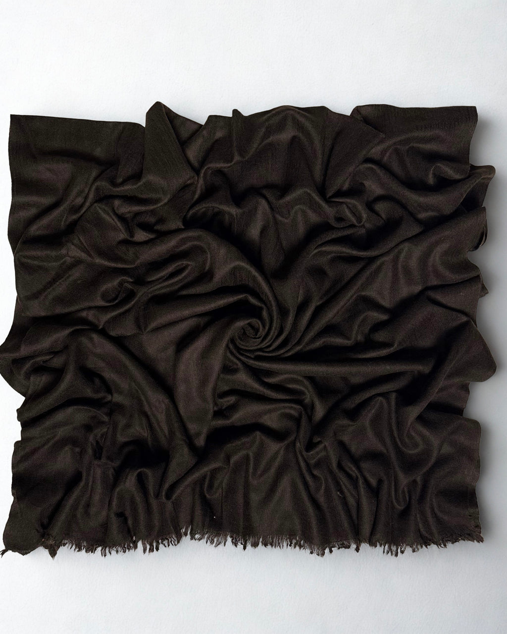 Espresso brown Swati Shahtoosh shawl gathered in a swirl, the matt chocolate cloth catching light along the folds