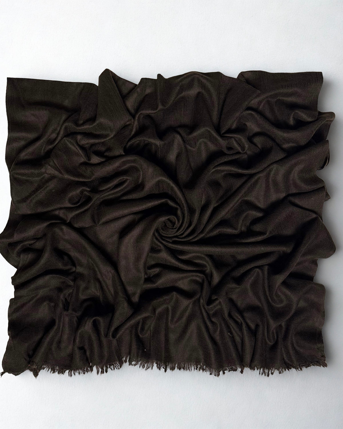 Espresso brown Swati Shahtoosh shawl gathered in a swirl, the matt chocolate cloth catching light along the folds
