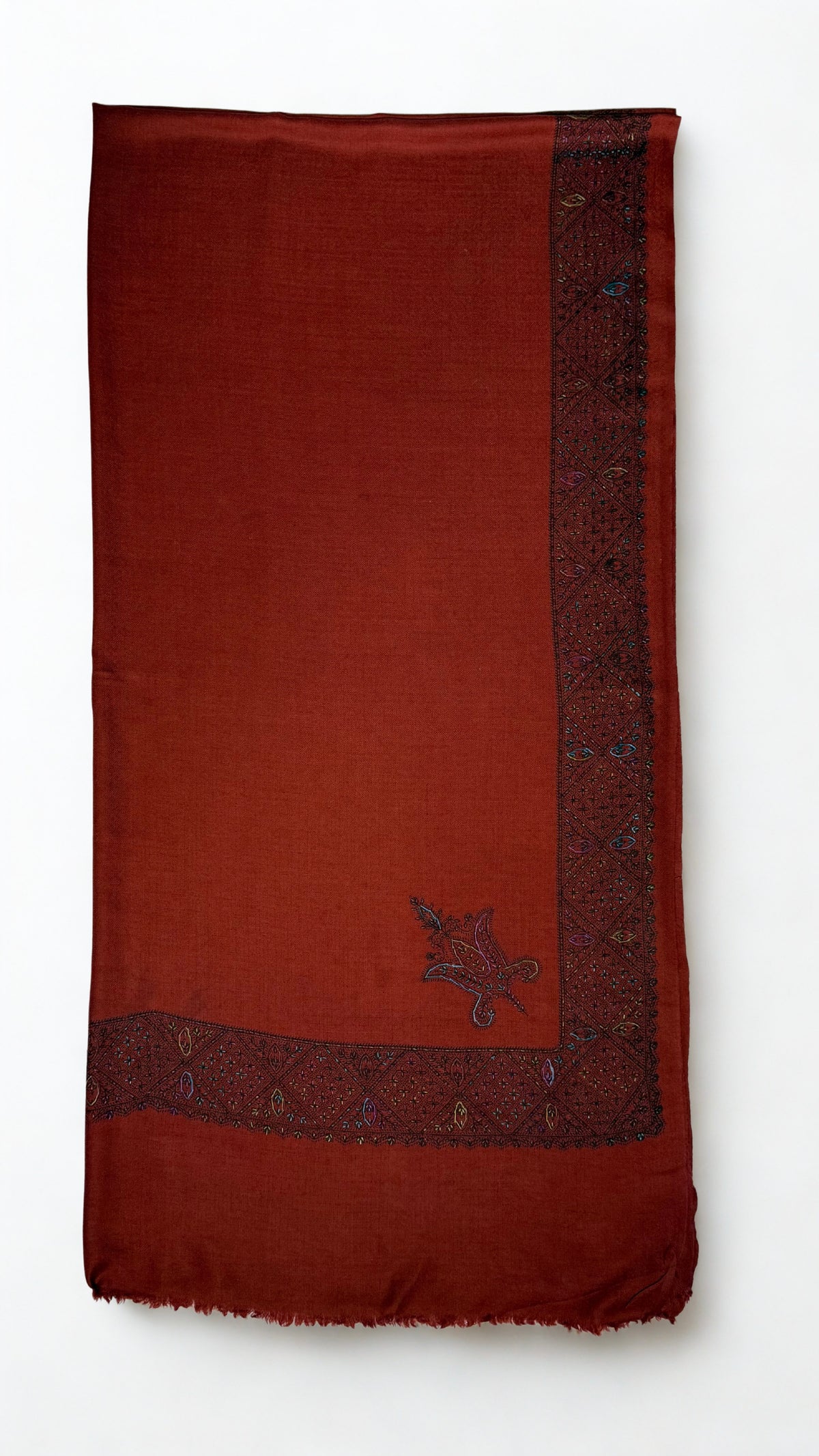 Rust Swati Shahtoosh shawl folded flat, the hand-embroidered lattice border running down one edge with a small paisley buta on the field