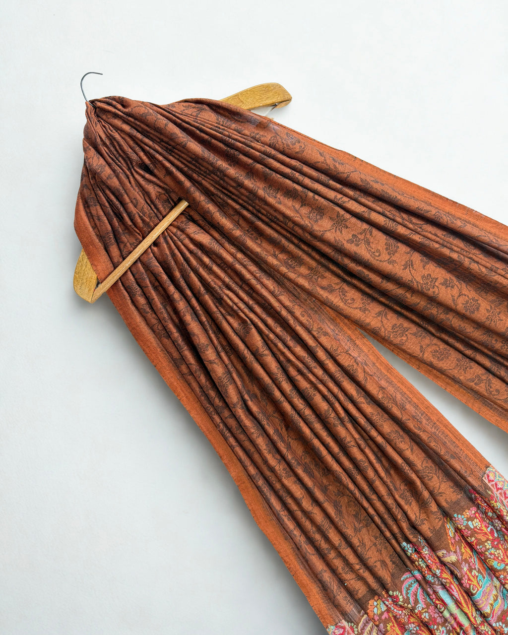Self-patterned flowering vine woven in darker brown across the rust field