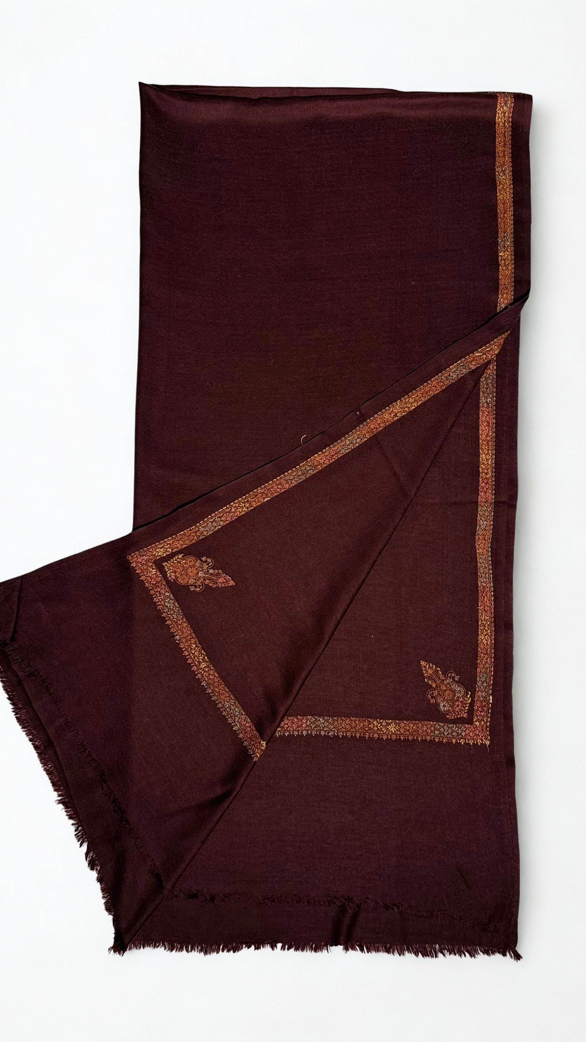 Deep maroon Swati Shahtoosh shawl folded back to show the corner buta and the embroidered border meeting at the corner