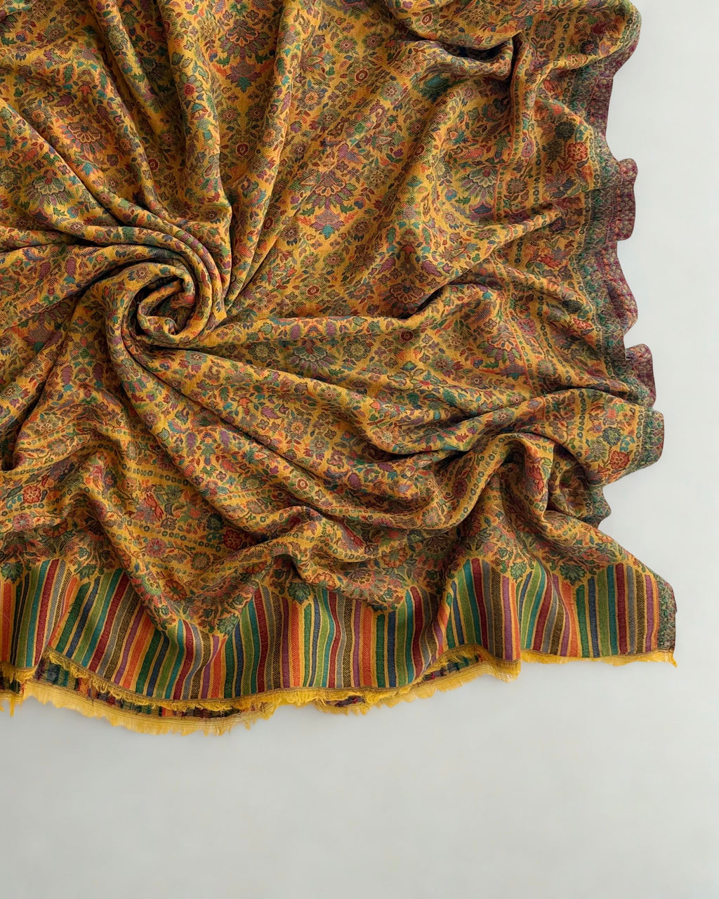 Marigold jamawar pashmina shawl folded lengthwise, showing the figured side border and the arched striped end