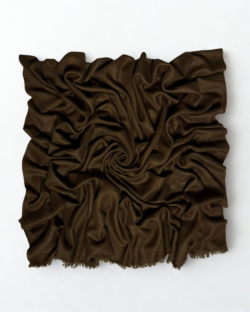 Warm brown Swati Shahtoosh shawl gathered in a swirl, the matt cloth catching light along the folds