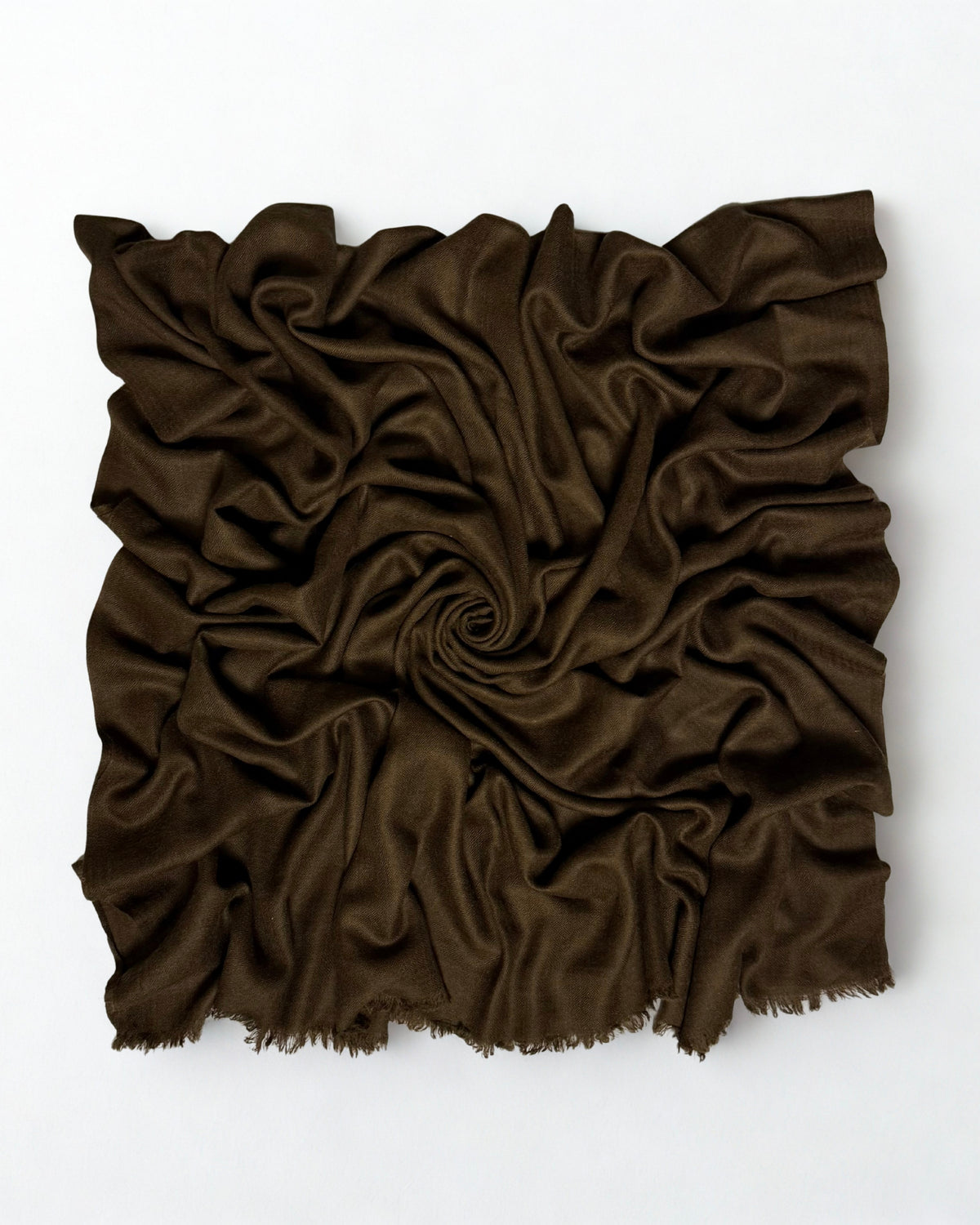 Warm brown Swati Shahtoosh shawl gathered in a swirl, the matt cloth catching light along the folds