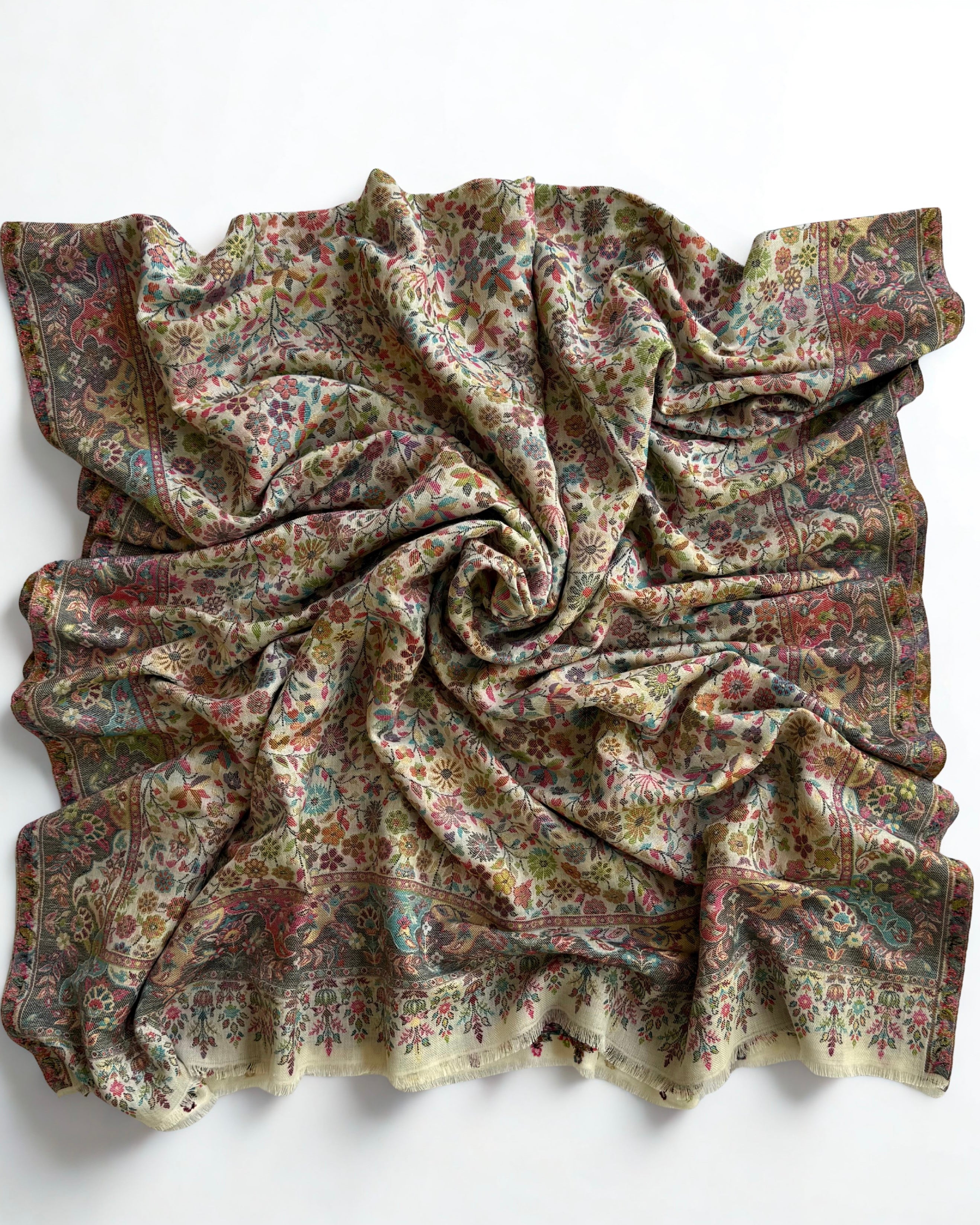 Corner detail of an ivory Zari Kani pashmina shawl, showing the slate border meeting the fringed end band