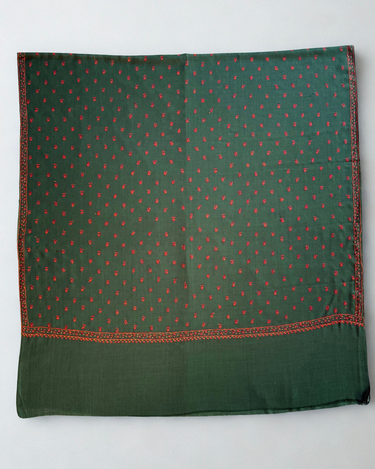Emerald pashmina shawl draped in soft folds, showing the crimson border and scattered buti