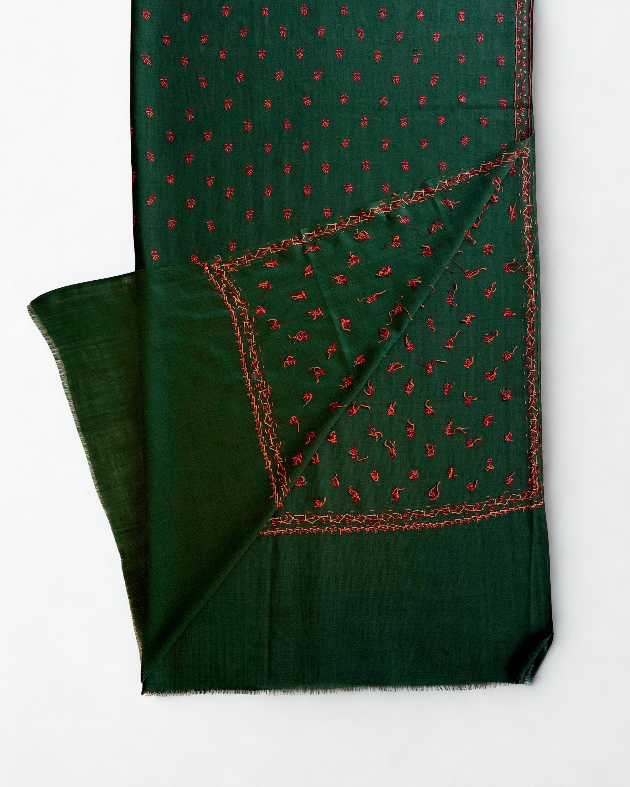 Emerald green hand-embroidered pashmina shawl laid flat, crimson buti across the field with a fine floral border