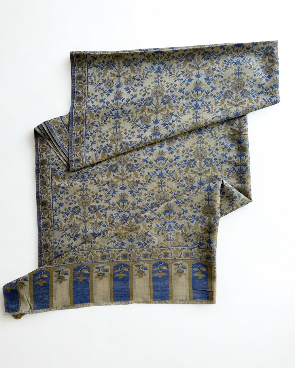 Ivory Kani pashmina shawl laid flat, handwoven cobalt and olive floral field with an arched end border