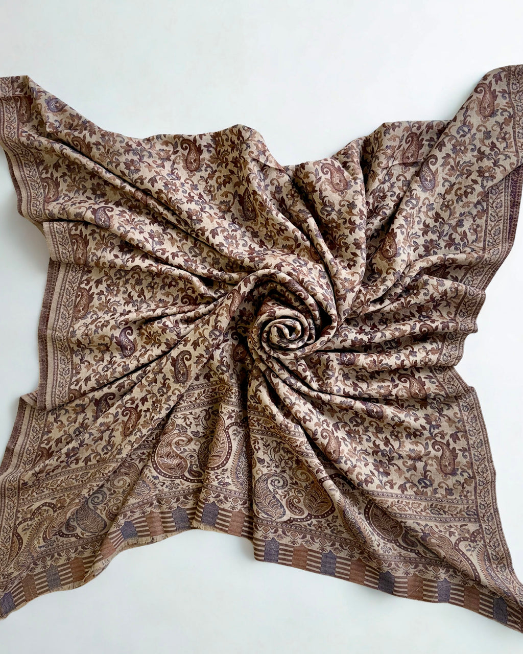 Close view of the Kani handwoven paisley buta in indigo and chestnut on a sand pashmina ground