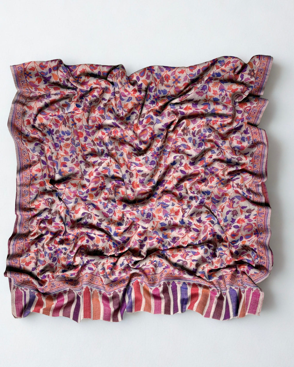 Close view of the Kani handwoven purple and coral flowering vines on a blush pashmina ground