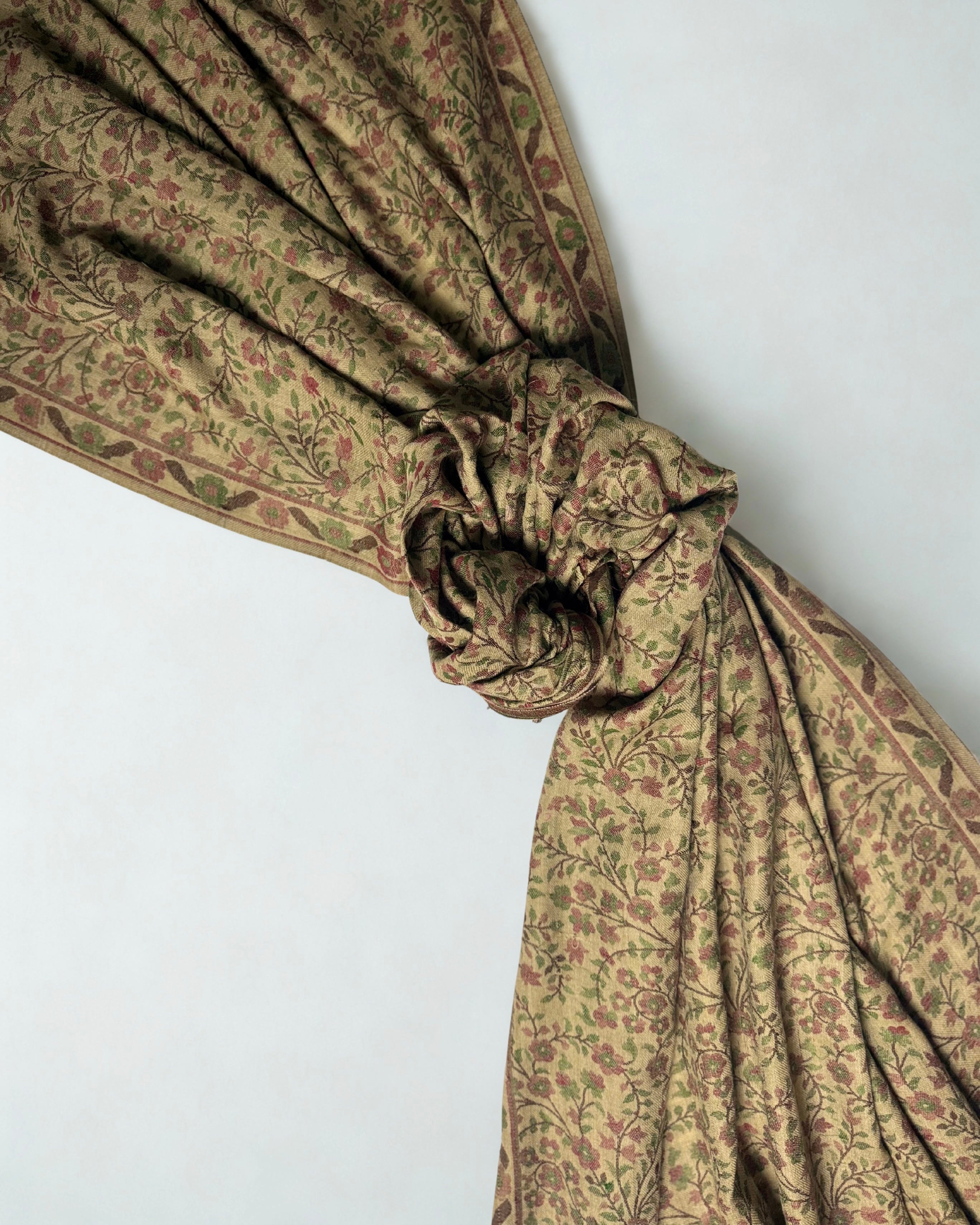 Antique gold Kani pashmina shawl knotted and fanned out, showing its full length and the arched end panel