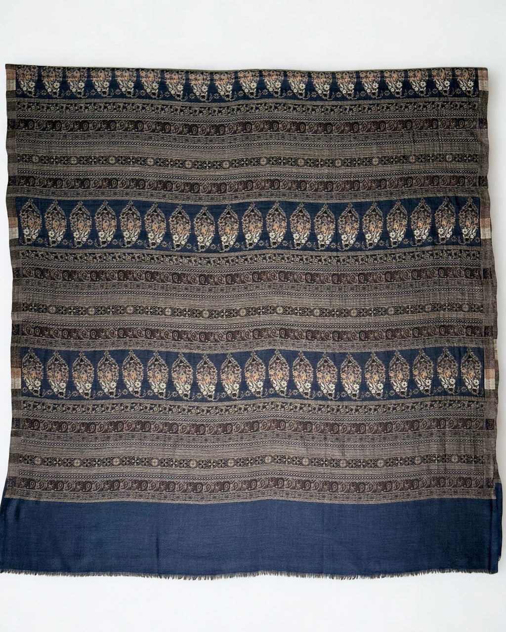 Close view of the bronze and stone paisley bands against deep indigo on a fine Indian pashmina shawl