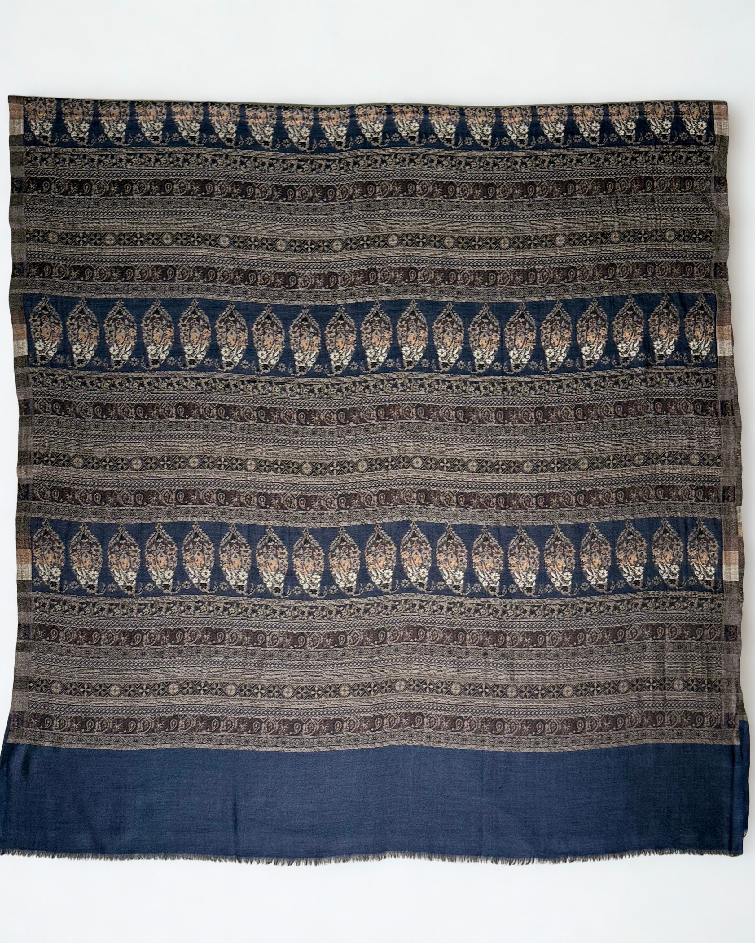 Close view of the bronze and stone paisley bands against deep indigo on a fine Indian pashmina shawl