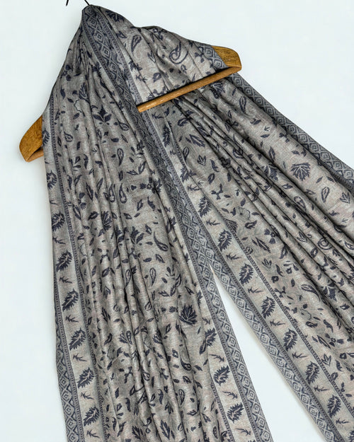 Stone and indigo Indian pashmina shawl laid flat, scattered paisley field framed by a leaf border with a broad striped end band