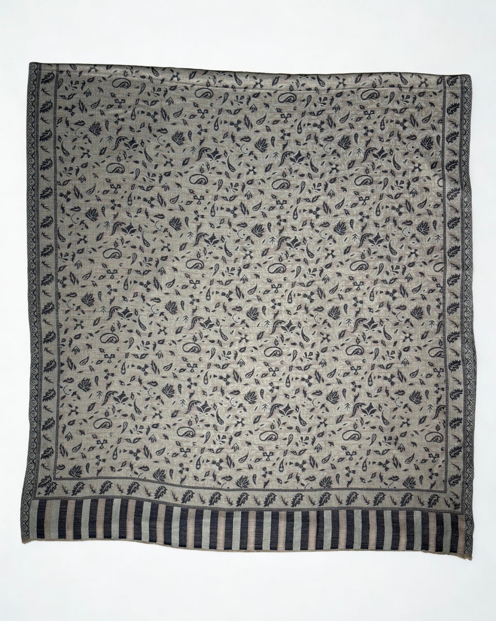 Close view of the indigo paisley motifs, leaf border and striped end panel on a stone grey pashmina shawl