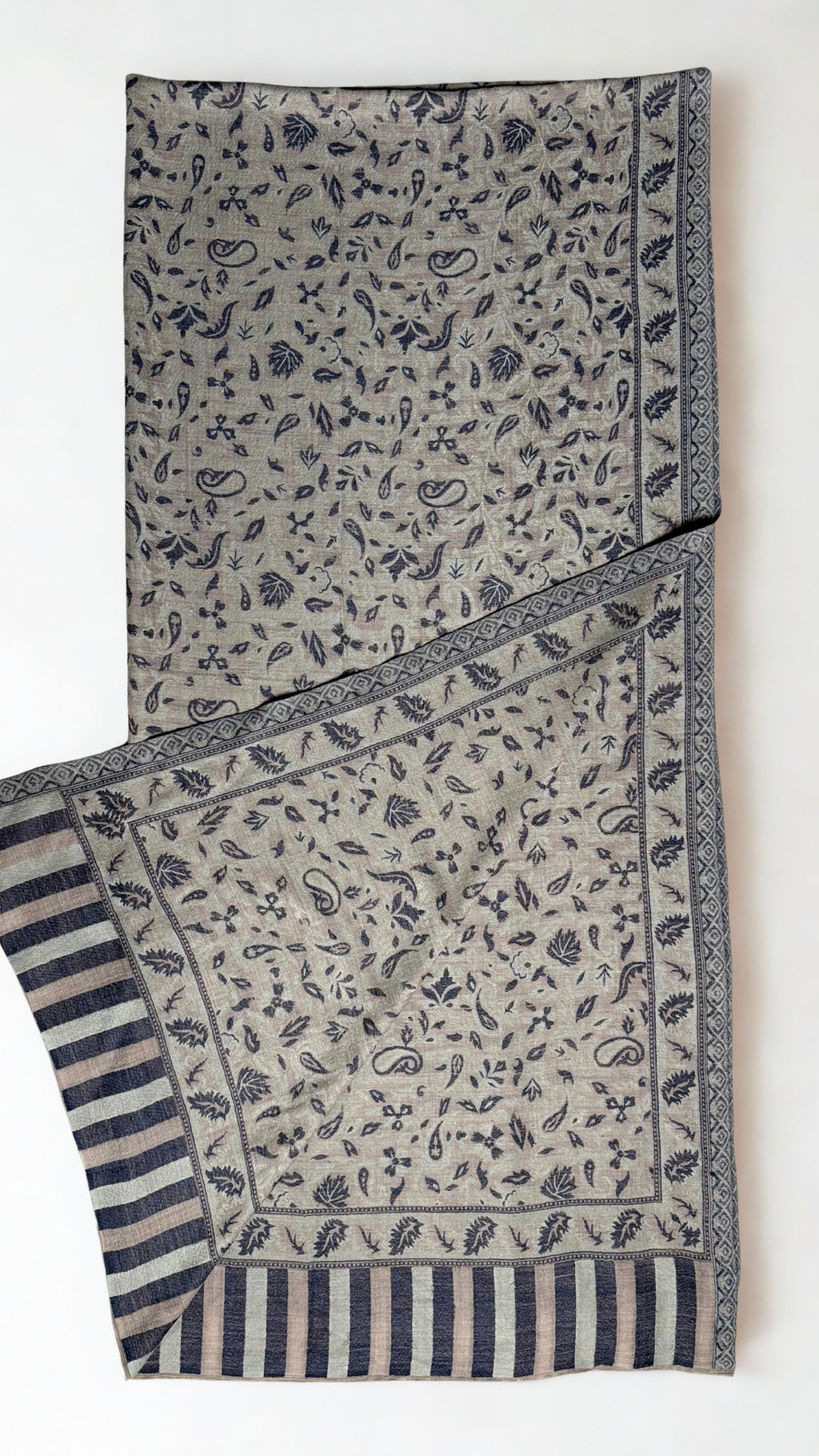 Stone grey Indian pashmina shawl folded lengthwise, indigo paisley field with a woven leaf border and striped end panel